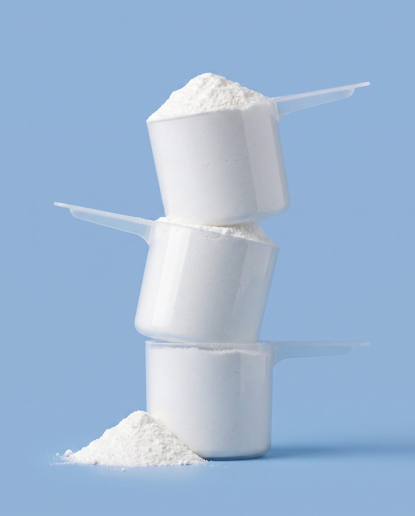 Three stacked measuring scoops filled with creatine monohydrate powder